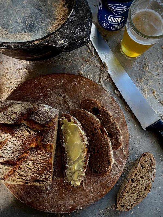 Citizen Sourdough bread cut up with butter spread on a slice, citizen beer can in the top right corner