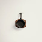 Small black cast iron skillet with wooden handle on a light gray background